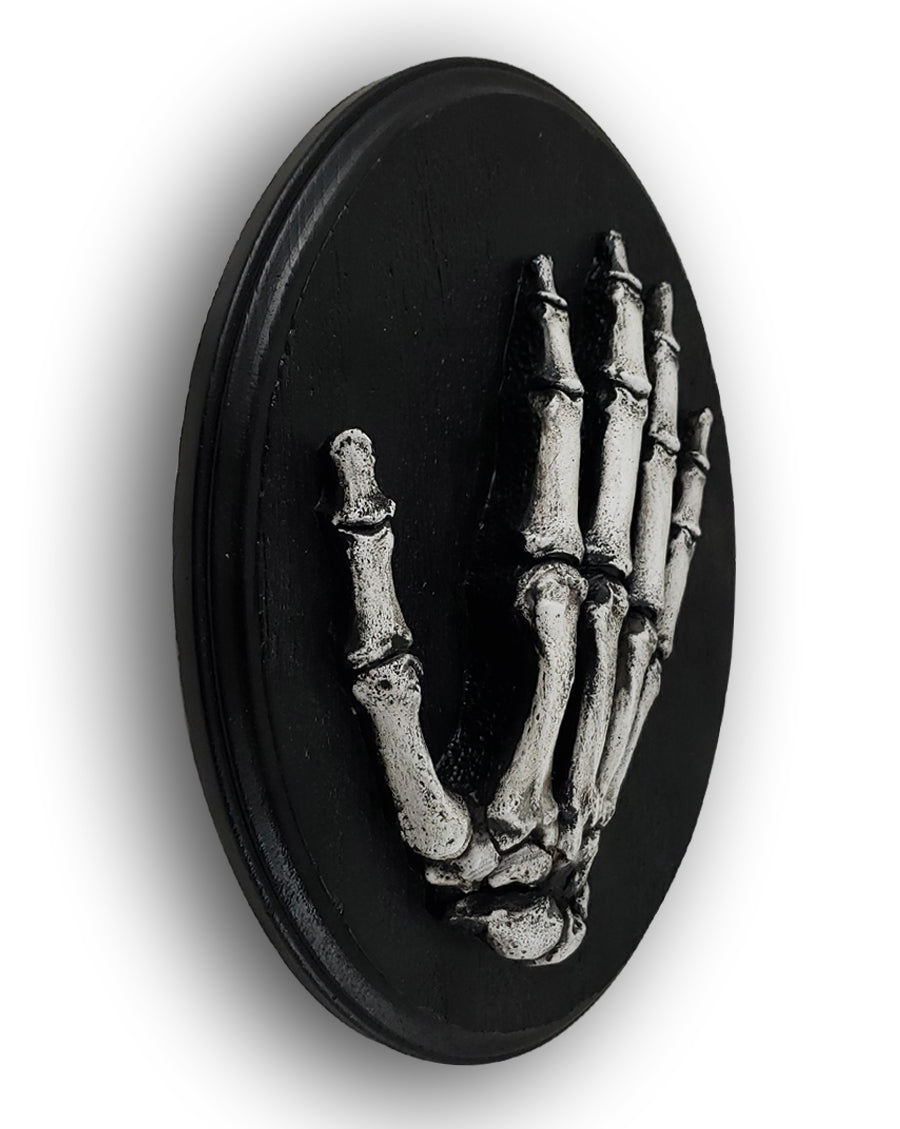 
                  
                    Oval skeletal hand plaque side view.
                  
                