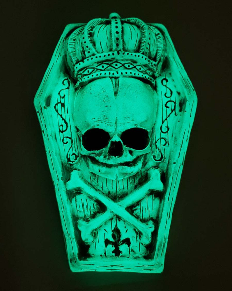 Glowing miniature coffin with skull and crossbones wearing a crown